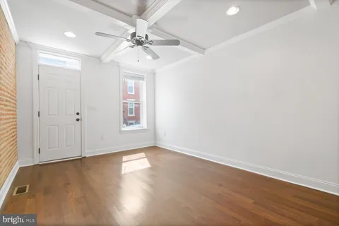 an empty room with wooden floor chandelier fan and windows