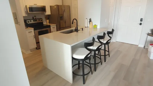a kitchen with stainless steel appliances kitchen island a table chairs in it and wooden floors