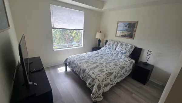 a bedroom with a bed a mirror on dresser and a window