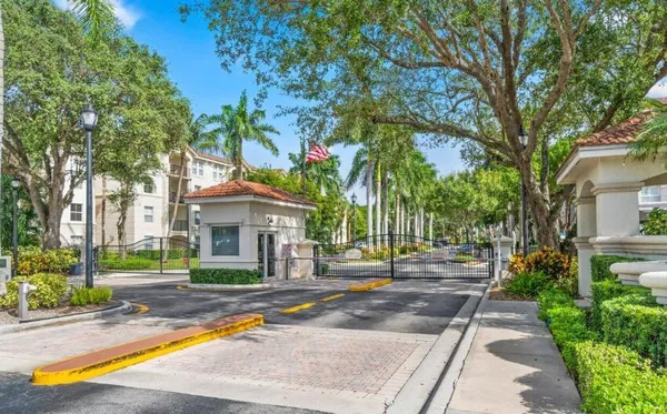 a view of a white house with a small yard and large trees