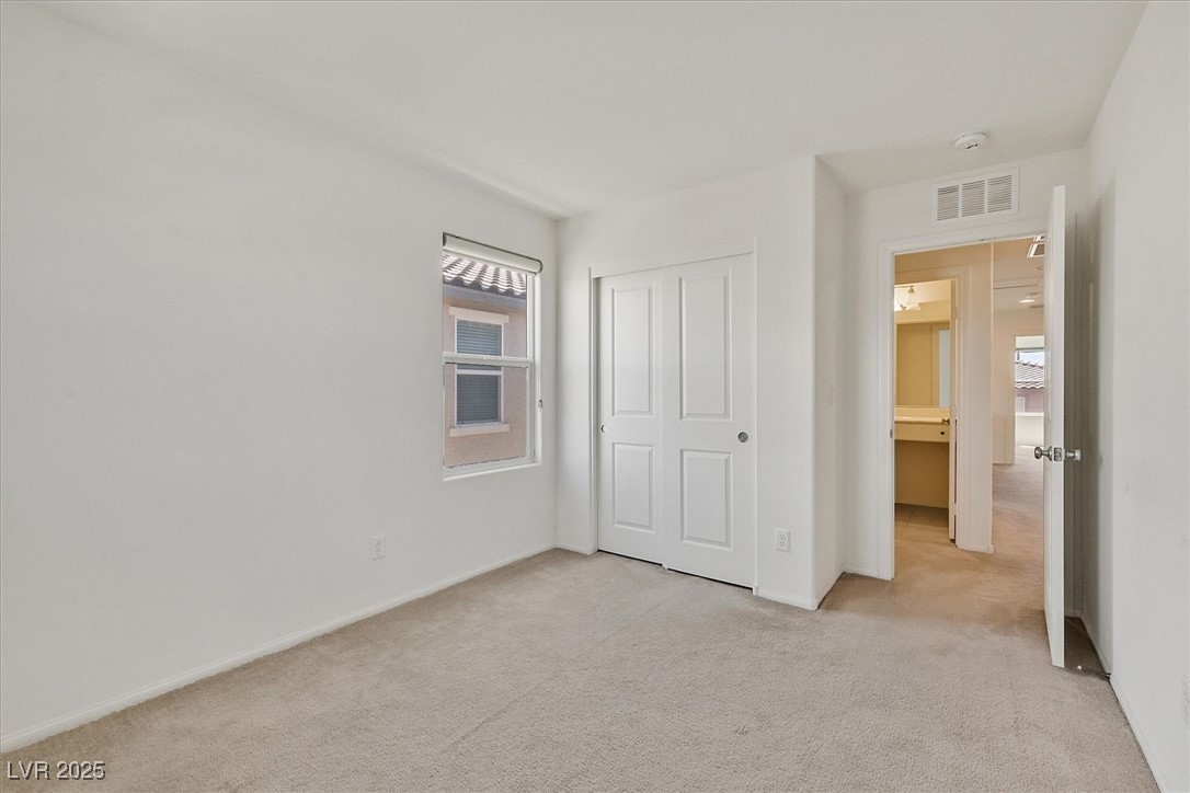8755 Spanish Ridge Avenue Las Vegas, NV 89148 - Photo 13 of 16 Unfurnished bedroom featuring light colored carpet, a closet, and baseboards