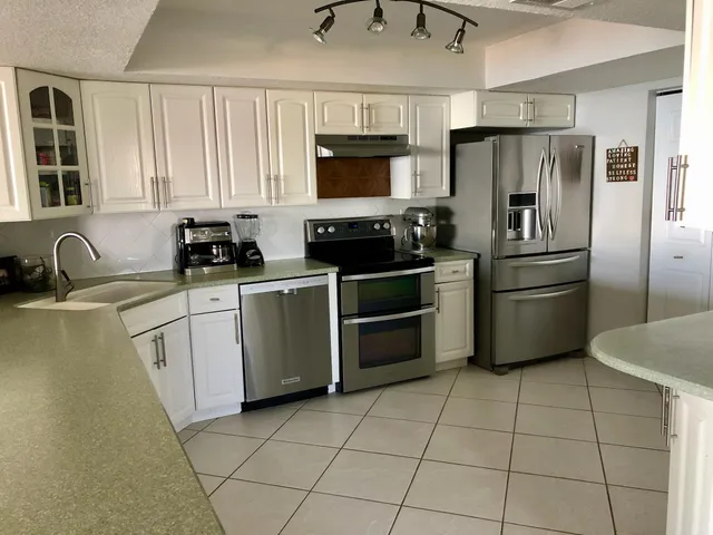 a kitchen with granite countertop a stove a sink and a refrigerator