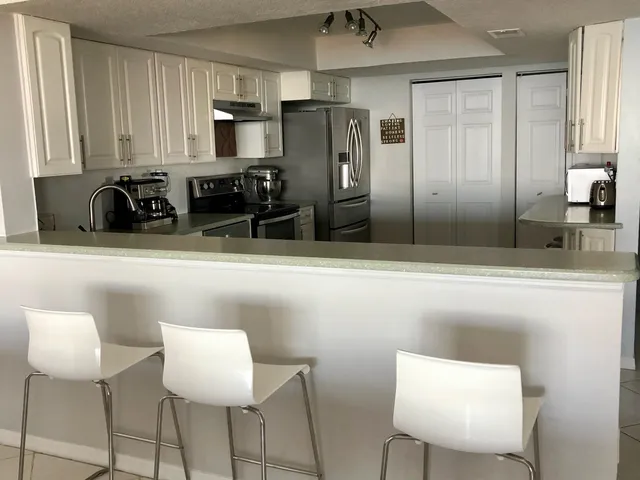 a kitchen with stainless steel appliances kitchen island granite countertop a refrigerator and a sink