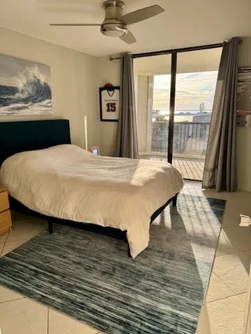 a bedroom with a bed painting on wall and a large window