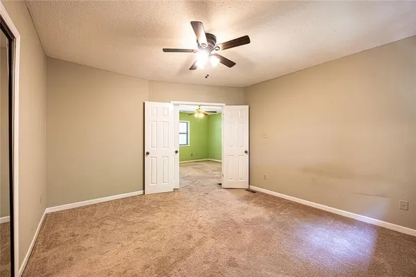 an empty room with ceiling fan and window