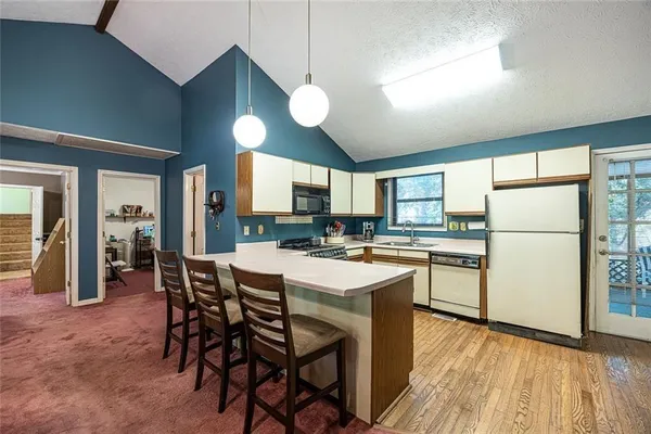 a kitchen with stainless steel appliances granite countertop a dining table chairs refrigerator and cabinets