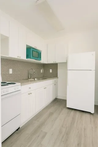 a kitchen with granite countertop white cabinets and white appliances