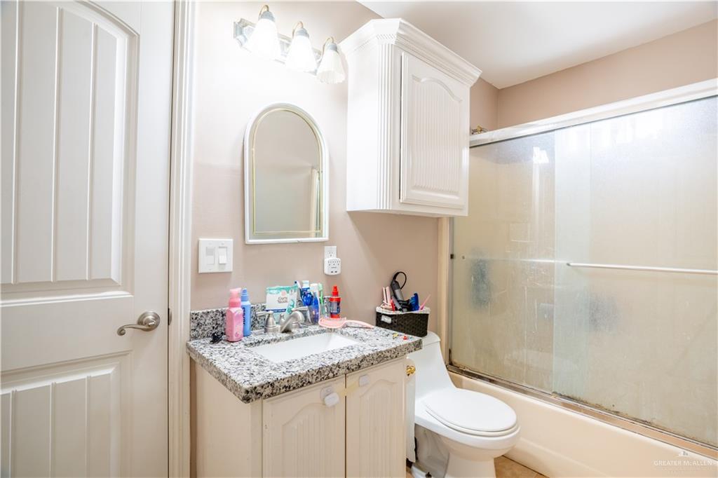 306 R Street Weslaco, TX 78596 - Photo 22 of 33 a bathroom with a granite countertop sink a toilet and shower