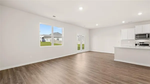 a view of an empty room with window and wooden floor