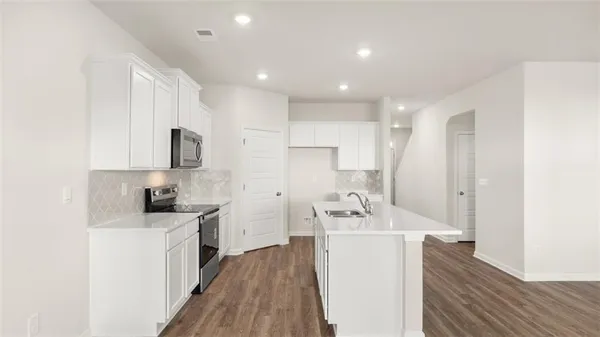 a kitchen with a sink a stove cabinets and wooden floor