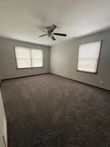 an empty room with windows and fan