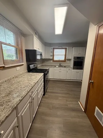 a large kitchen with a stove a sink dishwasher a microwave oven and a oven with wooden floor