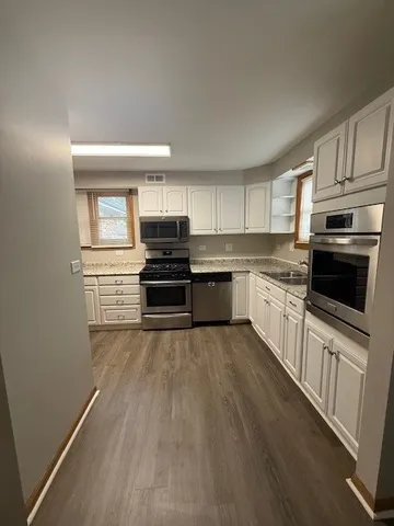 a kitchen with granite countertop a refrigerator and a stove top oven
