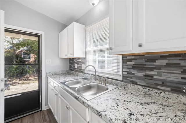 a kitchen with granite countertop a sink stove and cabinets