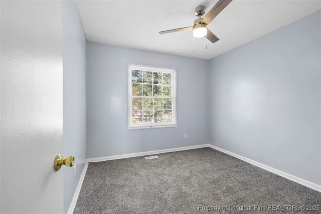 an empty room with a window and a ceiling fan
