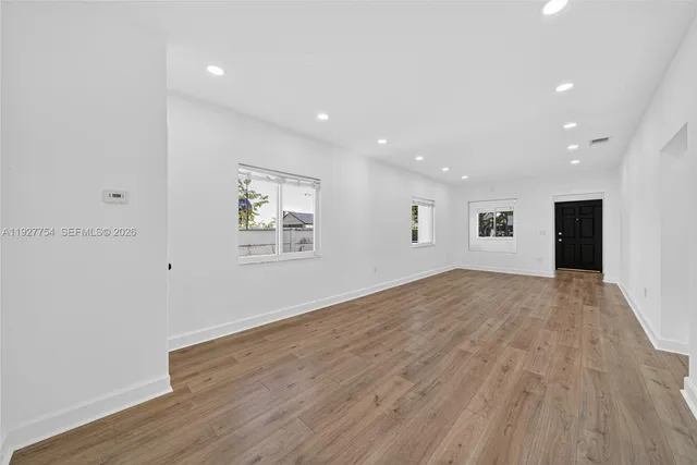 a view of an empty room with wooden floor and a window