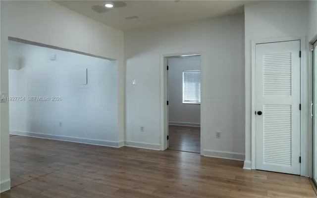 an empty room with wooden floor and closet area