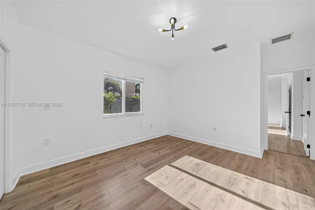 an empty room with wooden floor and window