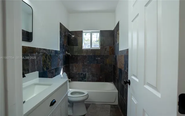 a bathroom with a sink a toilet a mirror and bathtub