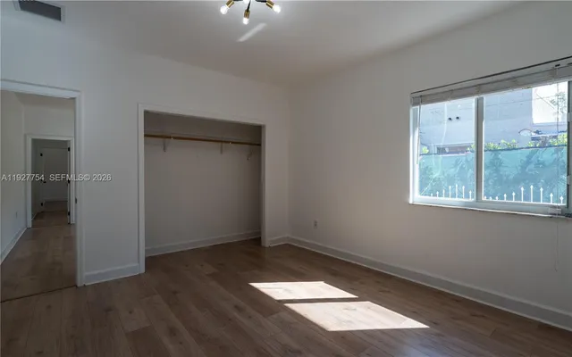 an empty room with wooden floor cabinet and windows