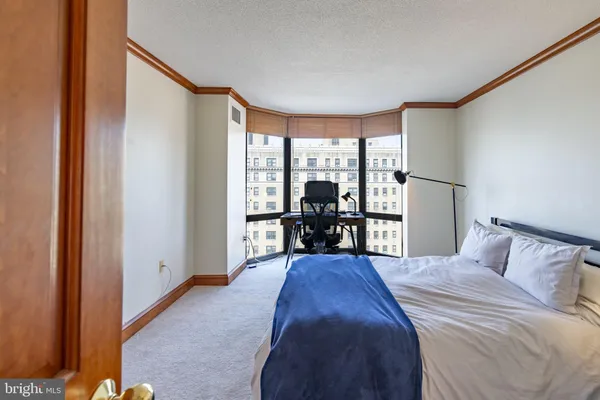 a bedroom with a bed and large windows