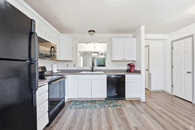 984 Independence Avenue Provo, UT 84604 - Photo 8 of 19 Kitchen featuring white cabinetry, wood-finish flooring, dark countertops, and a black appliance suite including a refrigerator, range, and dishwasher