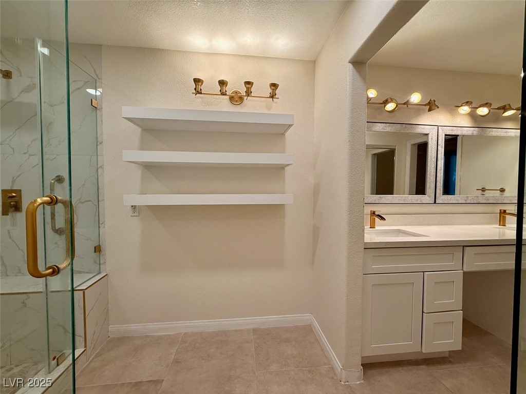 4969 Jeremy Drive Las Vegas, NV 89113 - Photo 33 of 73 Full bath featuring double vanity, a marble finish shower, light tile patterned flooring, and a textured ceiling