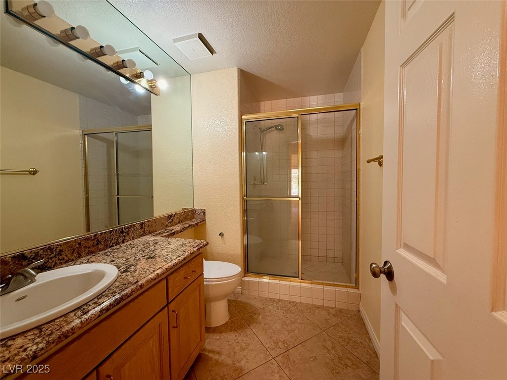 4969 Jeremy Drive Las Vegas, NV 89113 - Photo 53 of 73 Bathroom featuring a shower stall, vanity, a textured ceiling, and light tile patterned floors