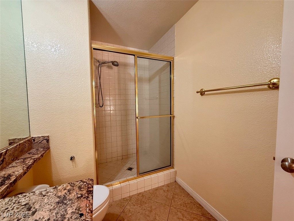 4969 Jeremy Drive Las Vegas, NV 89113 - Photo 54 of 73 Full bathroom with a textured wall, a stall shower, a textured ceiling, light tile patterned flooring, and vanity