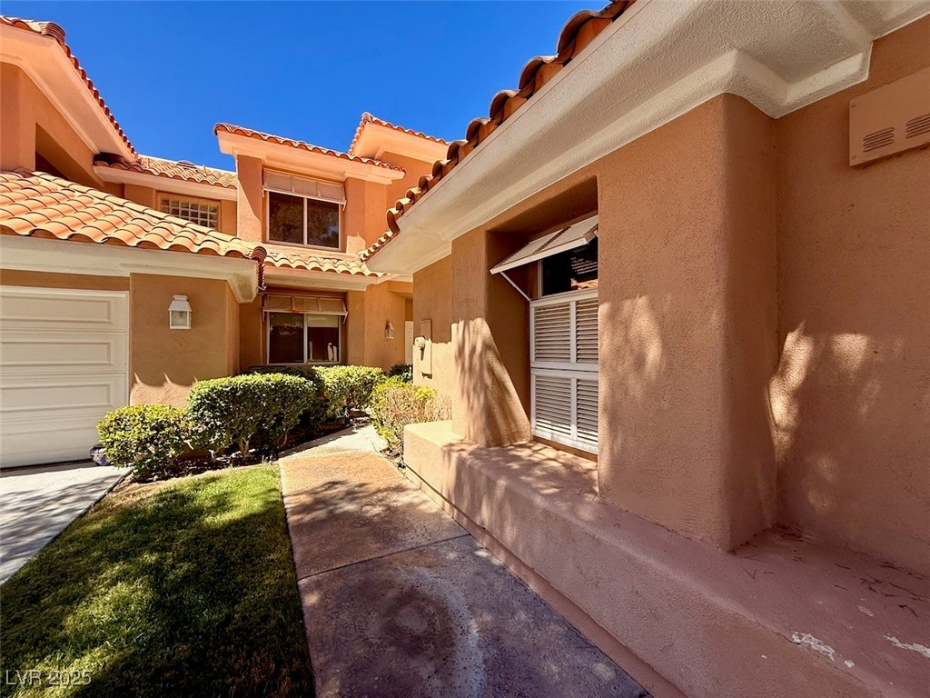 4969 Jeremy Drive Las Vegas, NV 89113 - Photo 8 of 73 Entrance to property featuring stucco siding, a tiled roof, and a garage