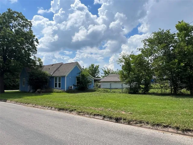 a view of a white house with a big yard and large trees