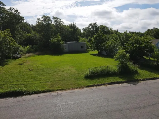 a view of a green field with trees in the background