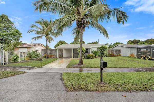 a front view of a house with a yard and palm trees