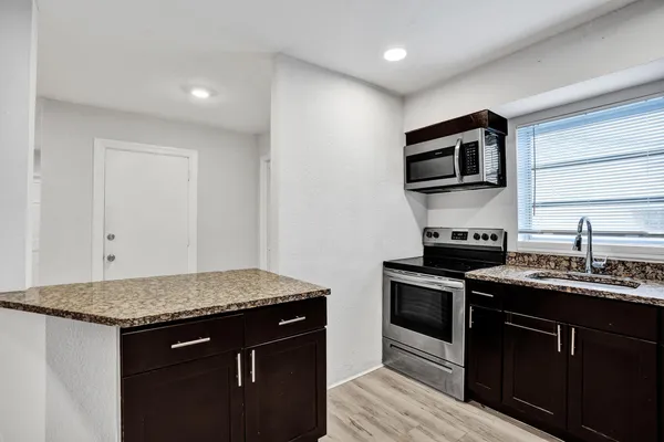 an empty room with wooden floor chandelier fan and windows