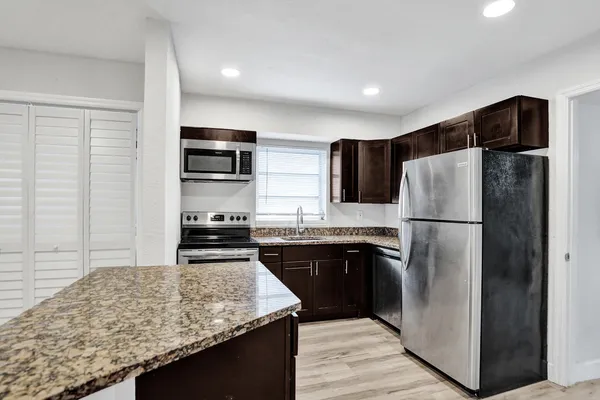 a kitchen with stainless steel appliances granite countertop a refrigerator stove a sink and a microwave