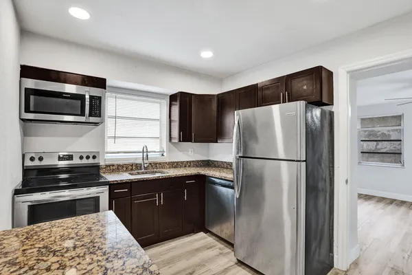 a kitchen with stainless steel appliances granite countertop a stove microwave and refrigerator