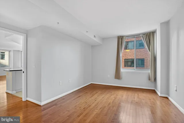 an empty room with wooden floor cabinet and windows