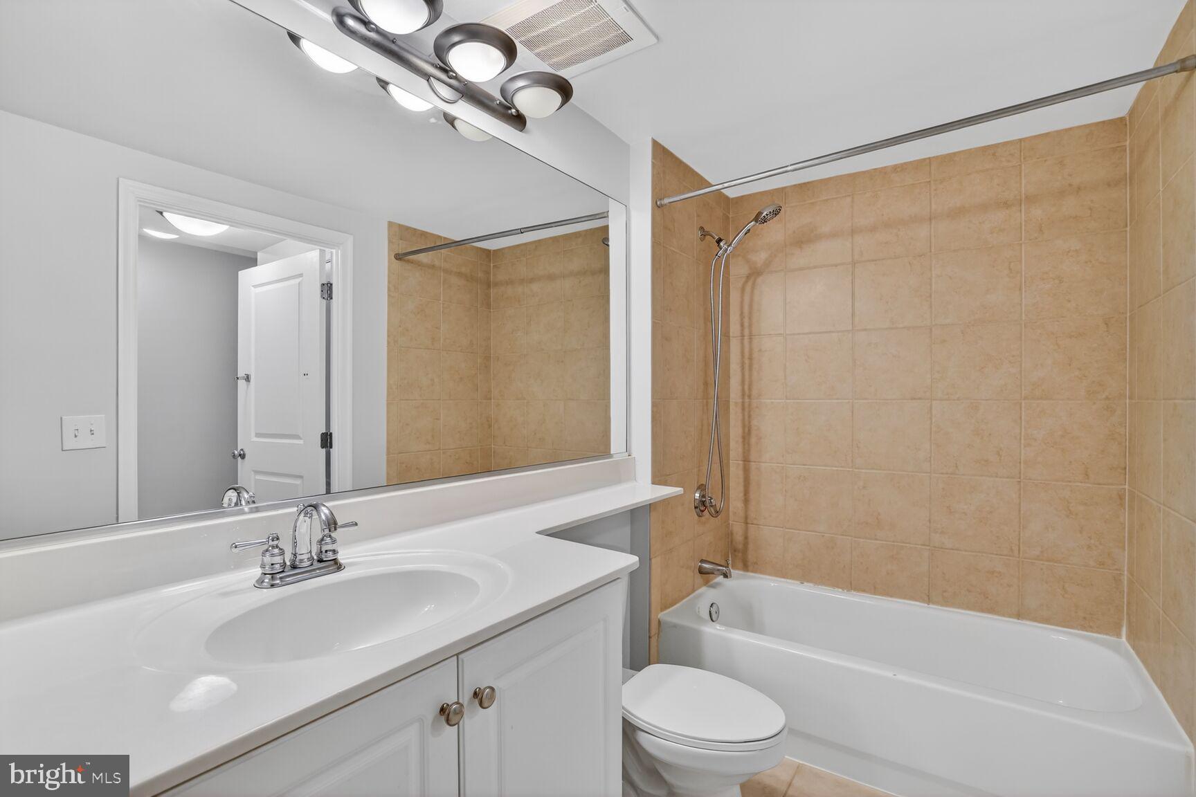 851 North Glebe Road, Unit 417 Arlington, VA 22203 - Photo 26 of 38 a bathroom with a bathtub shower sink vanity mirror and toilet