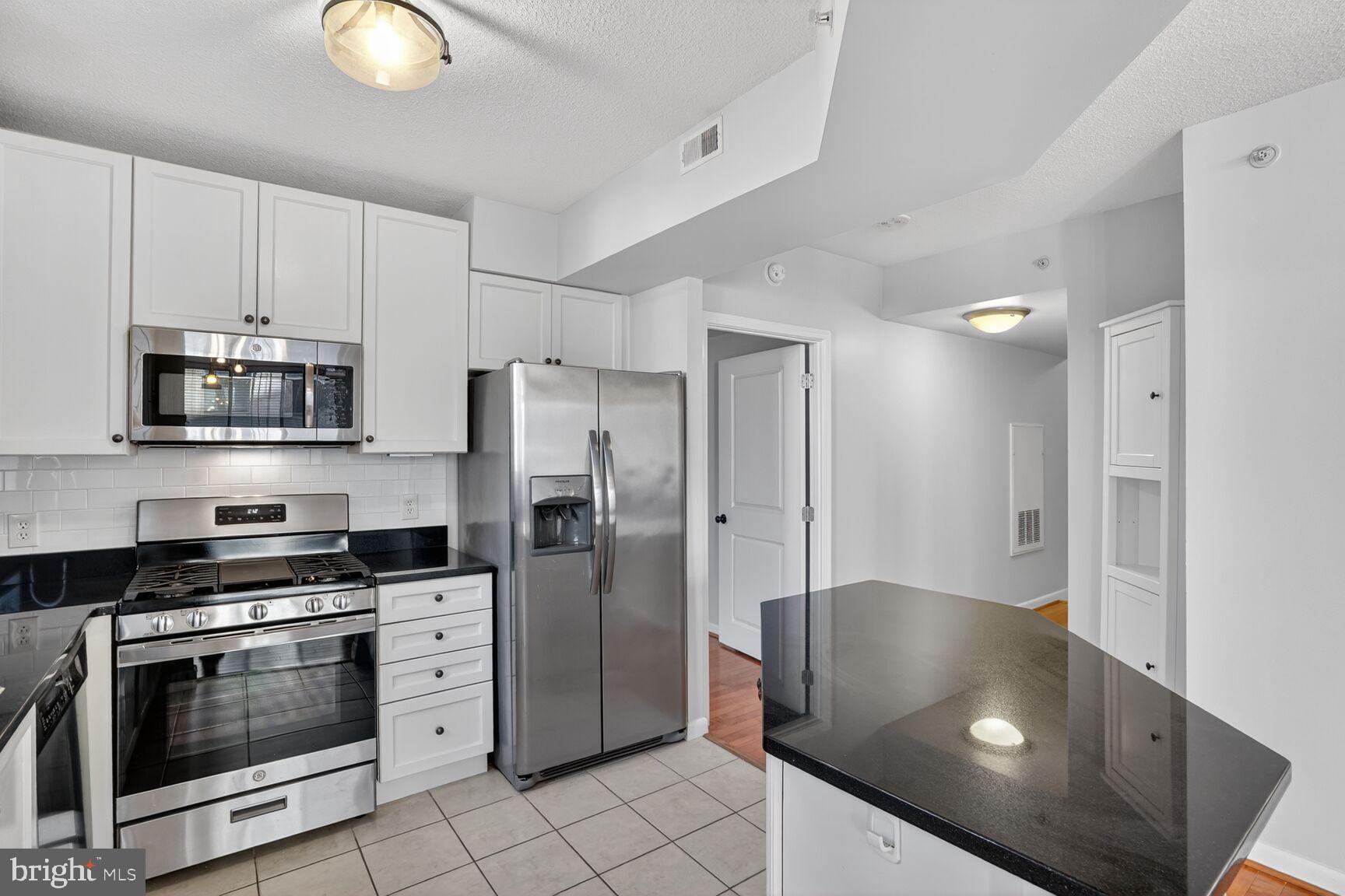 851 North Glebe Road, Unit 417 Arlington, VA 22203 - Photo 5 of 38 a kitchen with stainless steel appliances granite countertop a refrigerator a stove and a sink