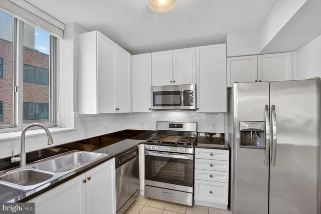a kitchen with granite countertop white cabinets white stainless steel appliances and a sink