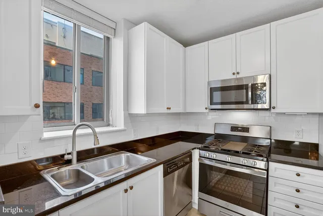 a kitchen with granite countertop a sink stove and microwave