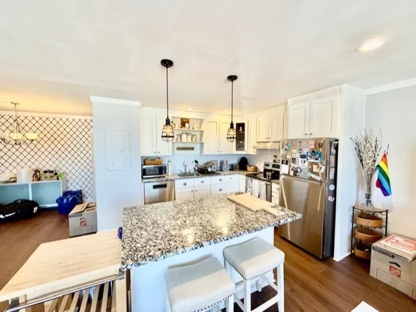 a kitchen with stainless steel appliances kitchen island granite countertop a table chairs and a refrigerator