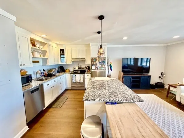 a open kitchen with stainless steel appliances kitchen island granite countertop a sink dishwasher and a black countertop with white countertops