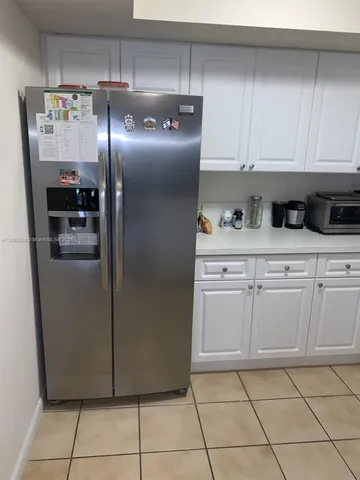 a kitchen with white cabinets and refrigerator
