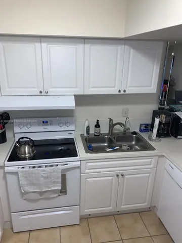 a kitchen with white cabinets and appliances