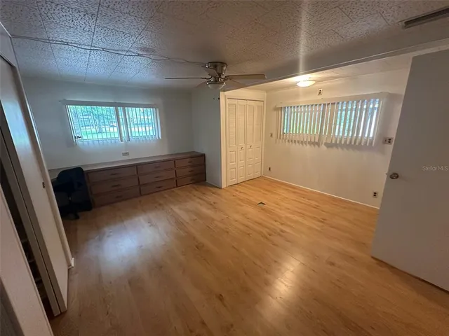 a view of empty room with wooden floor and fan