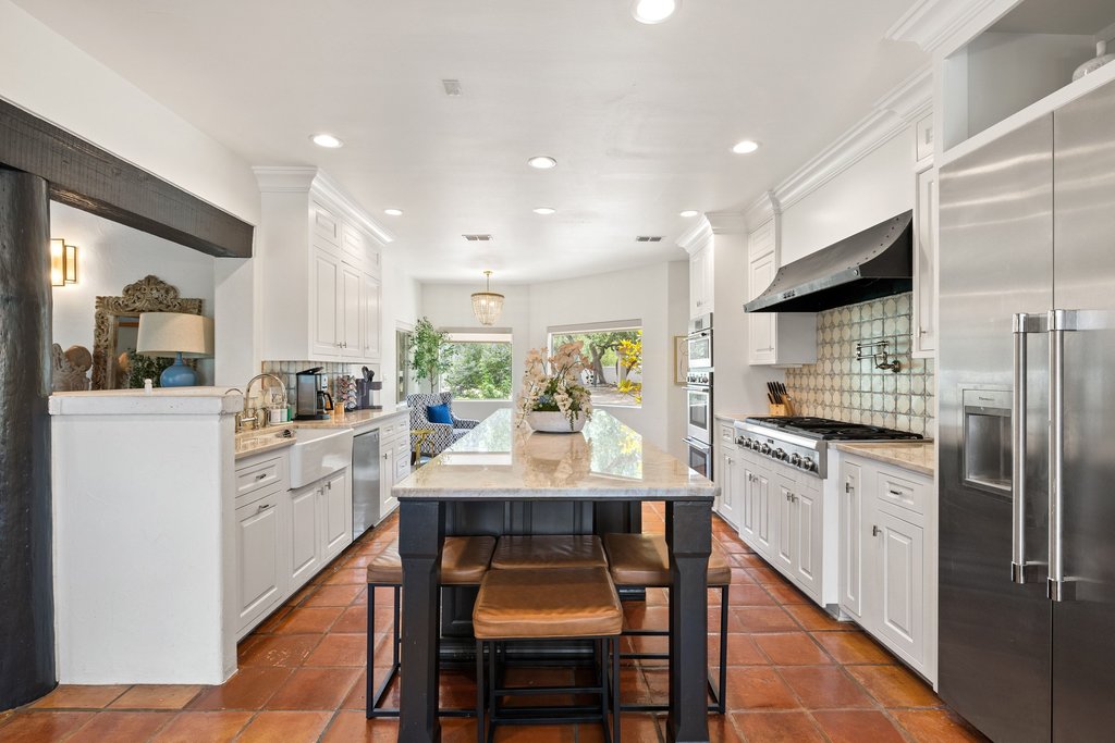 716 North Commons Ford Road Austin, TX 78733 - Photo 6 of 30 Spacious kitchen featuring an expansive center island with seating, a professional-grade range under a decorative hood, a large stainless steel refrigerator, white cabinetry, and terracotta-style flooring