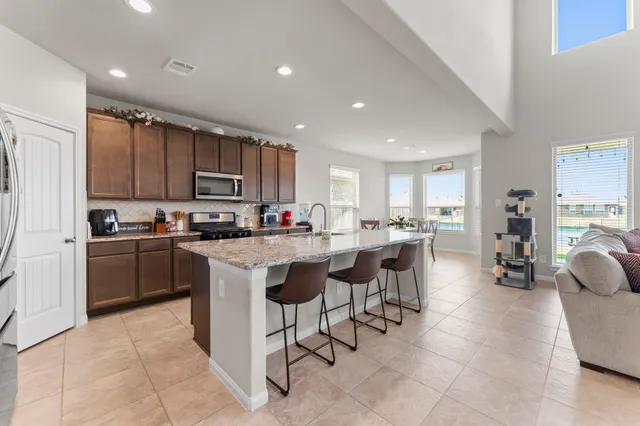 a kitchen with a sink a counter top space a center island stainless steel appliances and cabinets