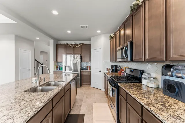 a kitchen with stainless steel appliances granite countertop sink stove top oven and cabinets