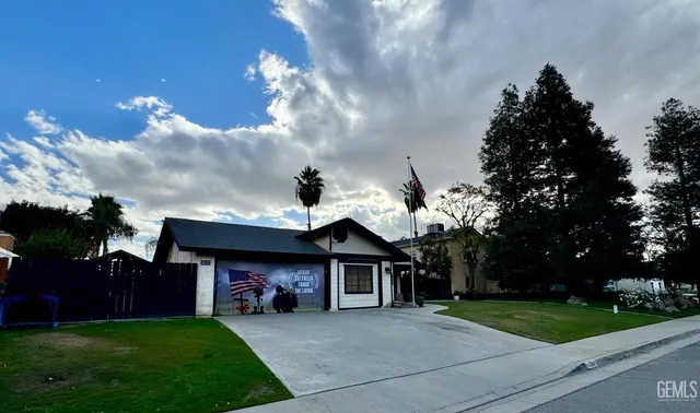 a view of a house with a small yard and a large tree